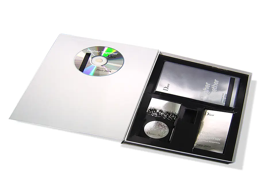 Dior - Coffret avec sachet contrecollé rembordé d’un papier couché R°V° – impression 1 couleur – pelliculage brillant – grille de calage en carton contrecollé de couché brillant imprimé et pelliculé – pastille porte-CD.